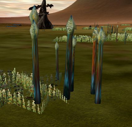 Tall, colorful crystal formations in a green landscape with sparse plants.