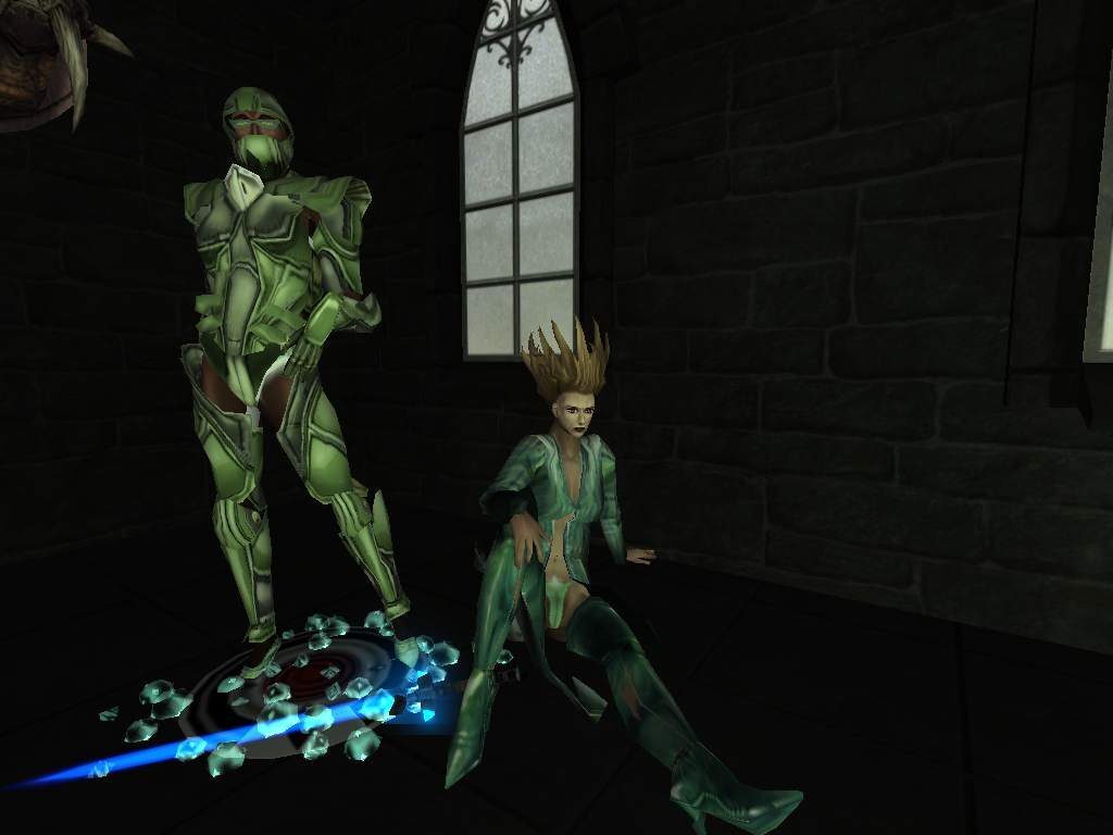 A green armored character stands next to a seated character with spiky hair in a dimly lit stone room.